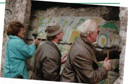 Reisegruppe als "Mauerspechte" mit Hammer und Meißel an der geöffneten Berliner Mauer