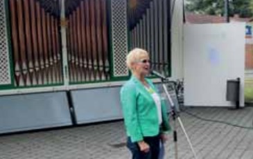 Ute Schallenberg begrüßt Gäste vor der Open-Air-Orgel beim 20-jährigen Jubiläum